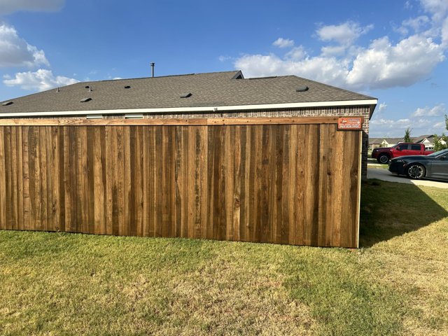 Wood fence beside a street with a Longhorn business sign.