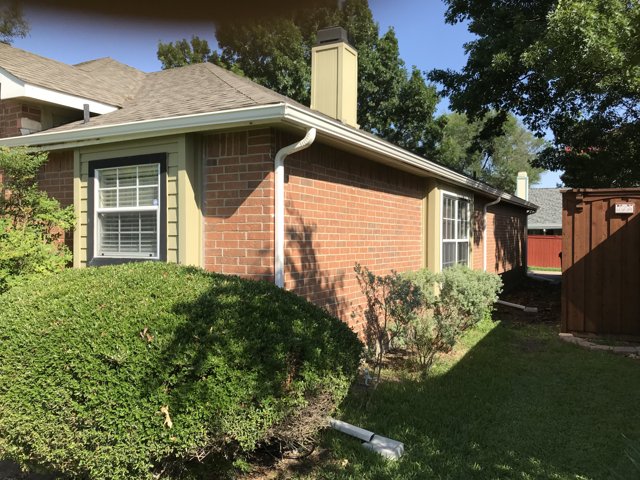 Exterior gutter and downspout along a brick house.
