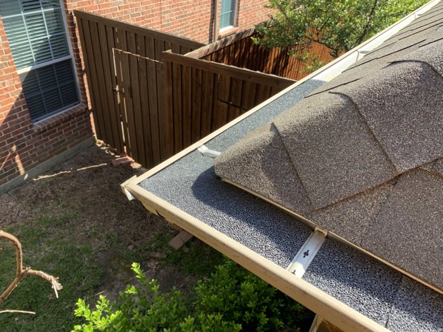Downspout beside an exterior fence.