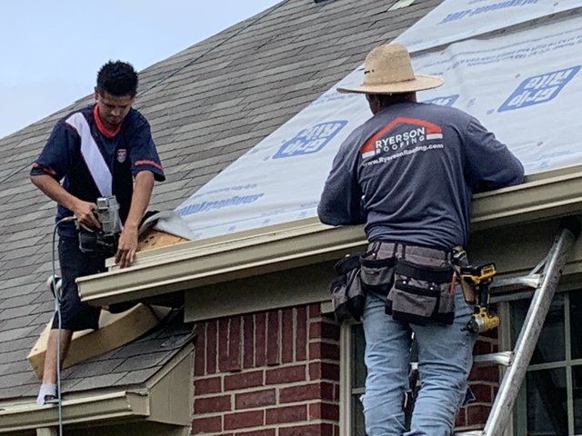 Roofing crew installing underlayment and shingles.