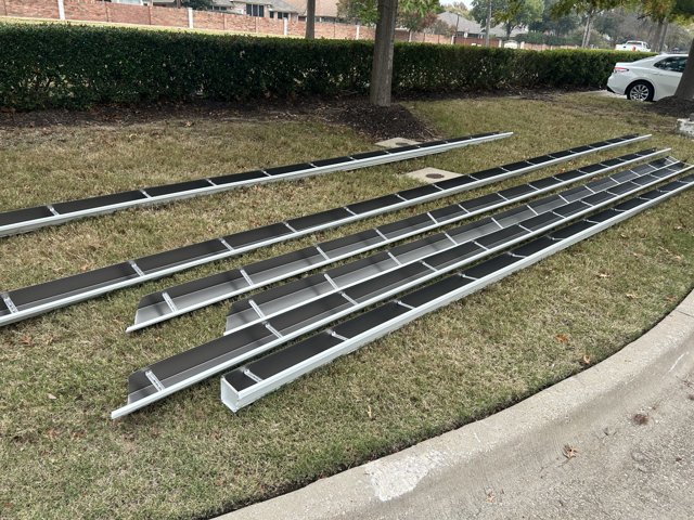 Gutter sections laid on a lawn beside a house.