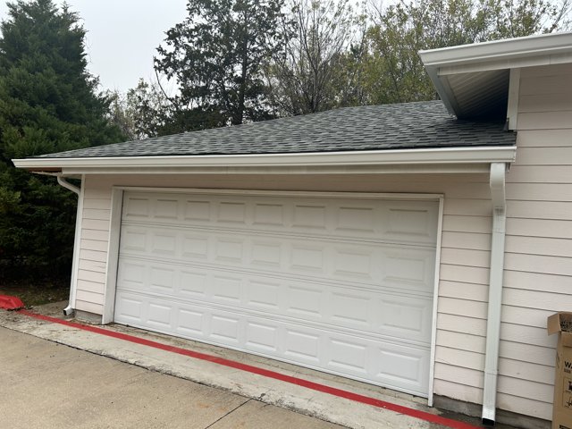 Gutter and downspout beside a closed garage.