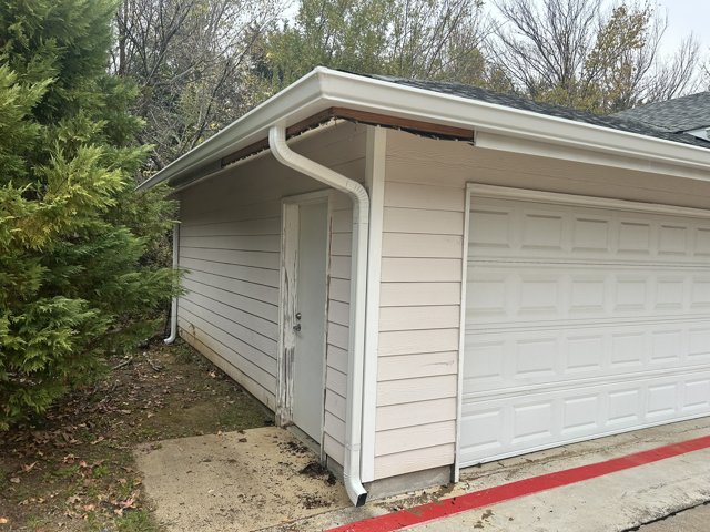 Exterior gutter along a house roof edge.