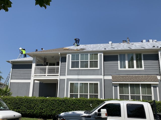Roofing crew working above the front exterior of a house.