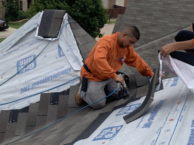 Roofing crew installing shingles on a residential roof.